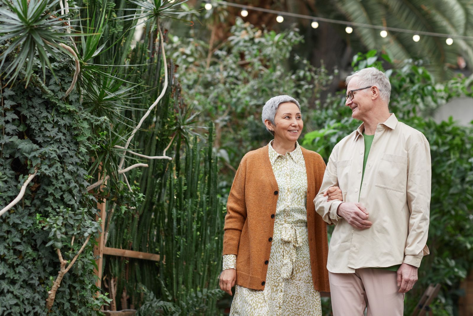 Retired couple walking together through a sunlit garden